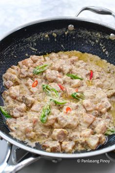 a pan filled with meat and vegetables on top of a stove