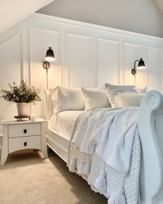 a white bed sitting in a bedroom next to two lamps on either side of it