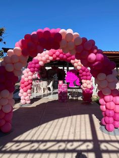 a pink and white arch with balloons on the side for an entrance to a party