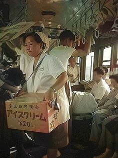 a group of people riding on top of a train next to each other with boxes in their hands