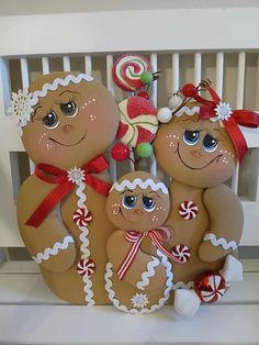 three gingerbread man and woman standing next to each other with candy canes in their hands