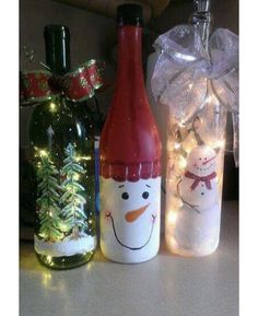 three wine bottles decorated with snowmen and christmas lights are sitting next to each other