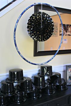 a black table topped with lots of black cups and hats next to a framed mirror