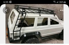 a white toy truck with black roof rack and ladders on it's sides