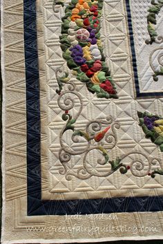 a close up of a quilted table runner with flowers and vines on the border