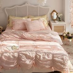 a bed with pink comforter and pillows in a bedroom