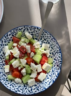 a blue and white bowl filled with cucumber, tomato and feta cheese