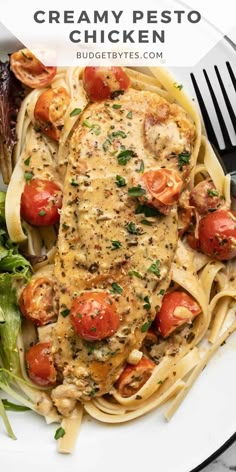 a white plate topped with chicken and tomatoes covered in sauce next to a green salad