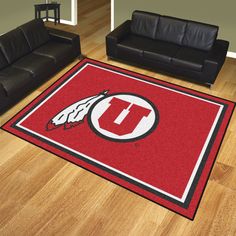 a living room with black couches and a red rug