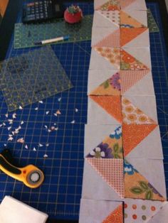 a pair of scissors sitting on top of a cutting board next to an orange and white quilt