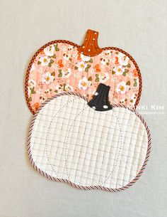 an orange and white patchwork pumpkin shaped applique hanging from a hook on a wall