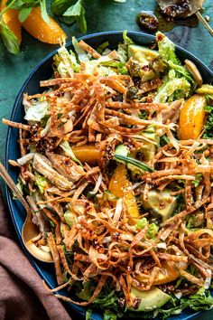 a salad with oranges, avocado and sesame seeds in it on a blue plate