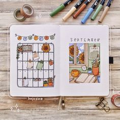 an open planner book sitting on top of a wooden table next to markers and scissors