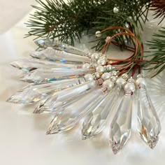 a close up of a christmas tree branch with crystal beads and pine needles on it