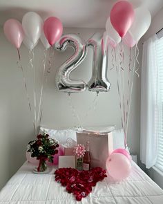 a bed topped with lots of pink and white balloons