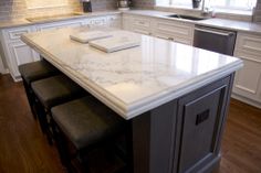 a kitchen island with stools in front of it