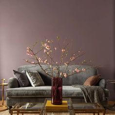 a living room with a couch, coffee table and flowers in a vase on it