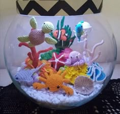 a fish bowl filled with lots of different types of crocheted sea animals and corals