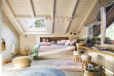 an attic bedroom with white walls and wooden beams, pink bedding, rugs on the floor