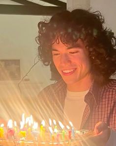 a man holding a birthday cake with lit candles