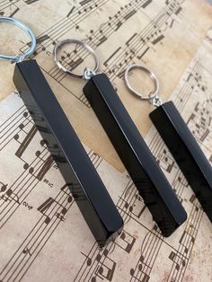 two black rectangular shaped key chains sitting on top of sheet music