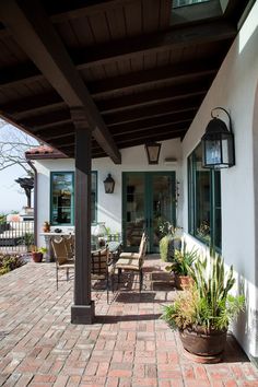 an outdoor patio with brick pavers, potted plants and hanging lanterns on the ceiling