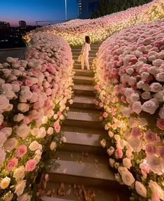 a woman is walking up some steps with flowers on it and lights in the background