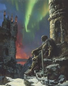 a man sitting on top of a snow covered hill next to a tall building with an aurora light in the background