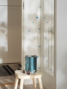 a blue can sitting on top of a wooden stool next to a white cabinet and door