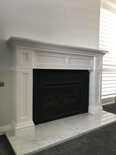 a white fireplace with a black mantle in a living room