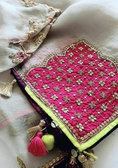 a pink and yellow scarf with tassels on it's end laying on a bed