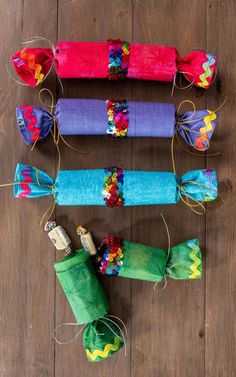 four colorful rolled up candy bars on a wooden table with string wrapped around the ends