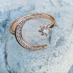 a gold ring with a star and moon on it sitting on top of a rock