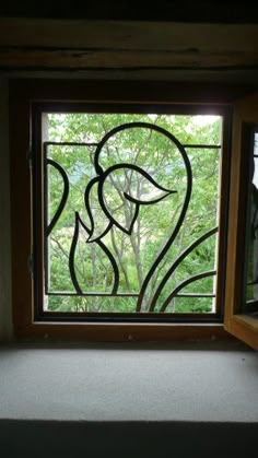 a window with a bird drawn on it and trees in the backgroung