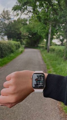 a person wearing an apple watch while standing on a path in the grass and trees