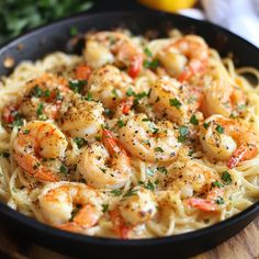 a pan filled with shrimp and pasta on top of a wooden table