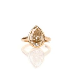 a yellow gold ring with a pear shaped brown diamond in the center, on a white background