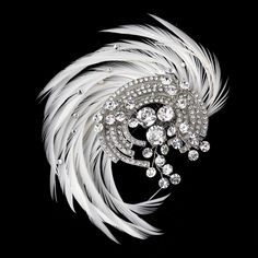 a brooch with white feathers and crystal stones on it's centerpiece, against a black background