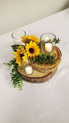 sunflowers and candles are arranged on a wooden slice