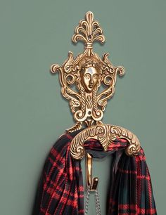 a scarf hanging on the wall with a gold head