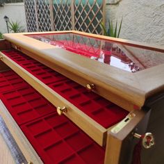 a large wooden chest with red velvet linings on the bottom and gold hardware at the top