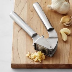 an onion slicer on a cutting board next to some garlic and cloves