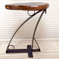 an iron and wood stool sitting in front of a white wall