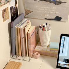 a computer monitor sitting on top of a desk next to a pile of books and pencils