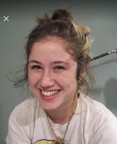 a woman smiling and holding a toothbrush in her hand while wearing a white t - shirt