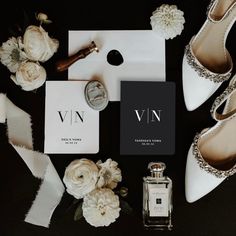 the wedding stationery is laid out with shoes, flowers and perfume bottle on it