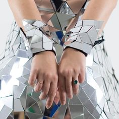 a woman with her hands on top of a mirror surface that is shaped like a triangle