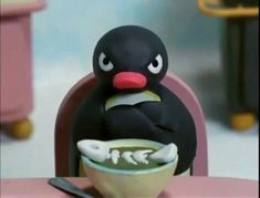 a penguin sitting at a table with a bowl of soup