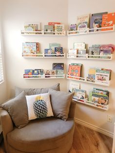 a chair with pillows and some books on the wall