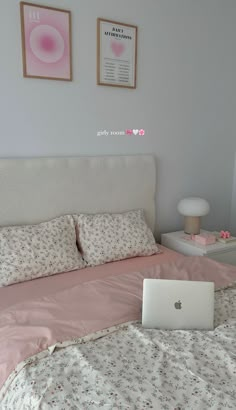 a laptop computer sitting on top of a bed next to pillows and pillowcases